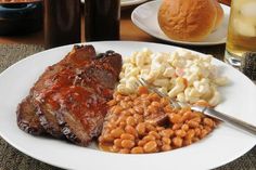 a white plate topped with ribs, beans and macaroni