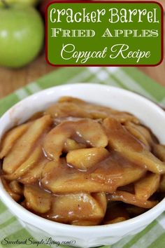 an apple dessert in a white bowl with caramel sauce on top and apples in the background