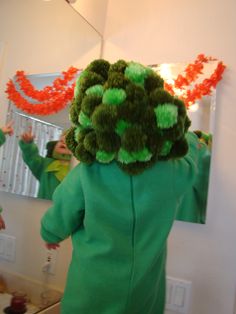 a child in a green costume is looking at herself in the mirror