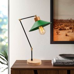 a green lamp sitting on top of a wooden table next to a framed photograph and record player