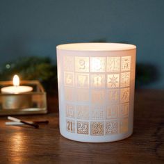 a lit candle sitting on top of a wooden table next to a tea light holder