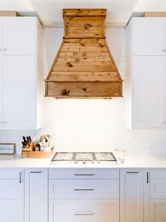 a kitchen with white cabinets and wooden stove hood