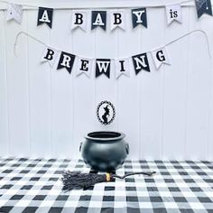 a black pot sitting on top of a checkered tablecloth covered floor next to a banner