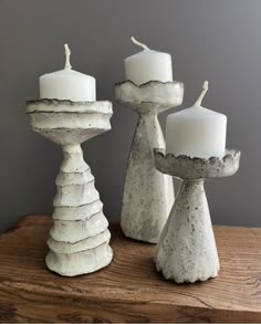 three white candles sitting on top of a wooden table