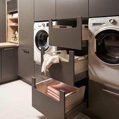 a washer and dryer in a small room with grey cabinets on the wall