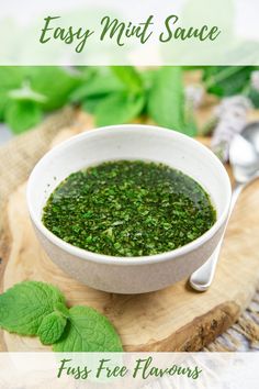 a white bowl filled with pesto on top of a wooden cutting board next to green leaves