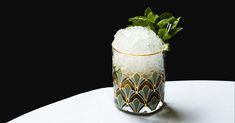 a glass filled with ice and mint on top of a table