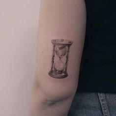 a woman's arm with an hourglass tattoo on the left side of her arm