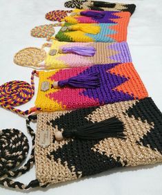 a row of multicolored purses sitting on top of a white table next to each other