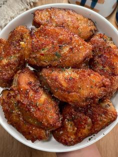 a white bowl filled with fried food on top of a wooden table