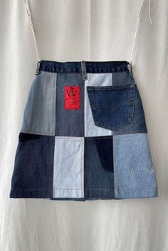 a patchwork denim skirt with red and blue patches on the side, hanging from a hanger