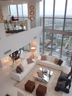 a living room filled with lots of furniture and large windows overlooking the cityscape