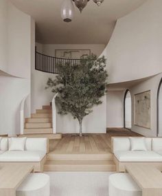 a living room filled with white couches and a tree in the middle of it