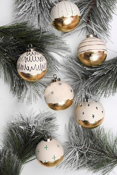 christmas ornaments hanging from the branches of a pine tree with gold and white decorations on them