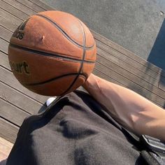 a basketball is being held up by someone's hand on a wooden deck outside