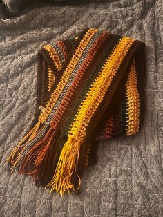 a crocheted blanket laying on top of a bed next to a gray comforter