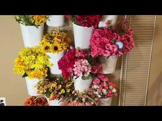 a bunch of flowers that are in some white vases on a wall next to a window