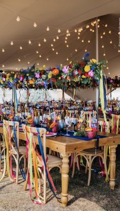 an outdoor event with tables and chairs covered in colorful streamers, lights and decorations