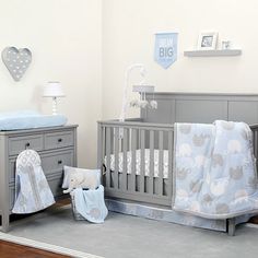 a baby's room with a crib, dressers and bedding in it