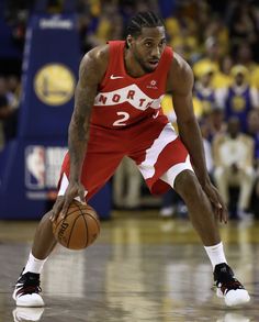 a basketball player holding a ball in his right hand and looking down at the ground