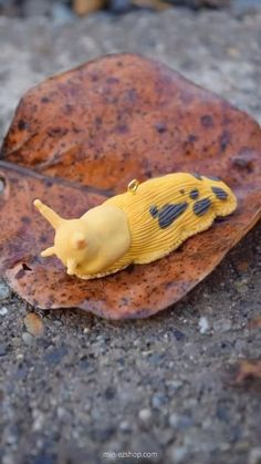 a yellow toy slug sitting on top of a leaf