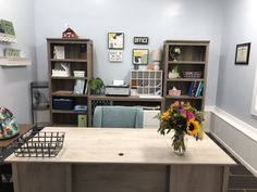 a vase with flowers sitting on top of a wooden table in front of bookshelves