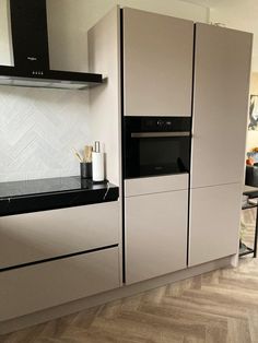 a modern kitchen with white cabinets and black counter tops, along with wood flooring