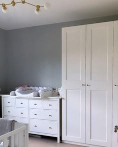 a baby's room with white furniture and gray walls