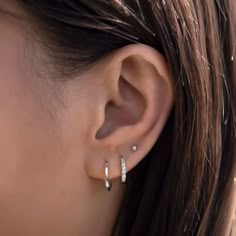 a close up of a person's ear with two small diamond hoops on it