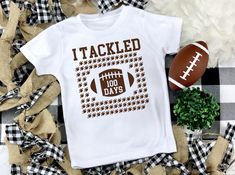 "Your little one will be proud to show his 100 day accomplishment in our \"I Tackled 100 Days\" football shirt. Our shirt features 100 footballs for your little one to count! This is a great way to tackle the rest of the year! Our shirts are all unisex fit and run true to size. Please be sure to check the measurement chart for an accurate fit. Best practice is to take a shirt that fits you well in the length and chest and lay it flat on the bed and measure as shown in the photos above. Once you 100th Day Of School For Boys, 120 Days Of School Cape, 100 Days Of School Shirt For Boys Sports, I Tackled 100 Days Of School, 100 Days Of School Shirt Football, 100 Days Shirt For Boys, 100 Days Of School Shirt Sports, 100th Day Of School Shirts For Boys, 100 Items On A Shirt 100th Day