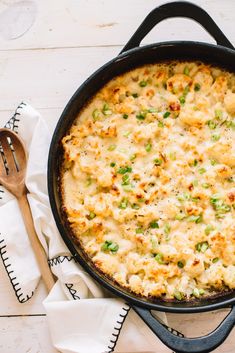 a casserole dish with green onions and cheese in a cast iron skillet