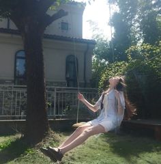 a woman sitting on a swing in front of a house