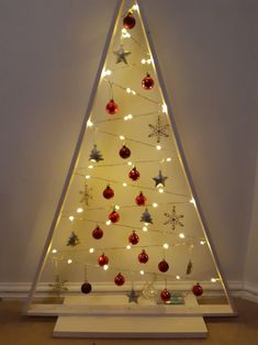 a lighted christmas tree with red and white baubles on it's sides