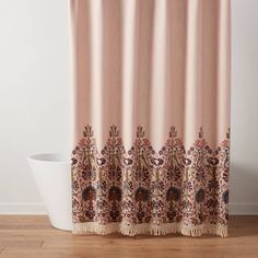 a pink shower curtain with an ornate design on the side and fringe trim around it