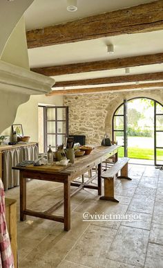 an open kitchen and dining area with stone walls, flooring and exposed beams on the ceiling