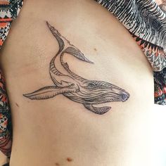 a woman's stomach with a tattoo of a whale and waves on the side