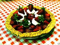 strawberries and cream in a yellow bowl on a checkered tablecloth