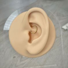 a fake ear with a gold ring on it's middle part, sitting on top of a table