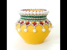 a yellow vase filled with lots of different colored beads