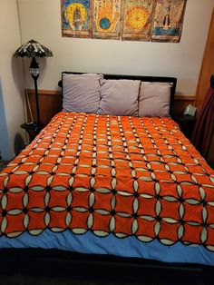 a bed with an orange bedspread and two pictures on the wall above it