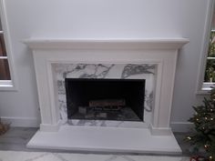 a white fireplace with marble surround and mantel