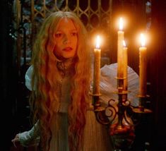 a woman with long blonde hair standing in front of candles