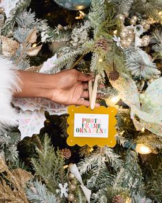 a hand holding a sign on top of a christmas tree