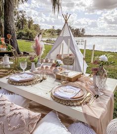 a table set up with plates and napkins for an outdoor dinner party by the water