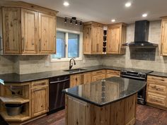 a large kitchen with wooden cabinets and black counter tops, an island in the middle