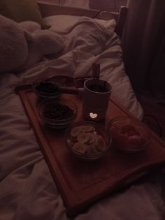 the tray is full of snacks and drinks on the bed in the dark night time