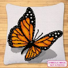 a cross stitch pillow with an orange butterfly sitting on it's back and the words symbolic image, not a photo