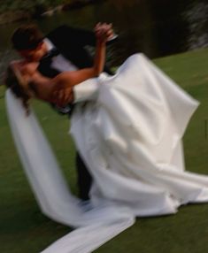 the bride and groom are kissing on the grass