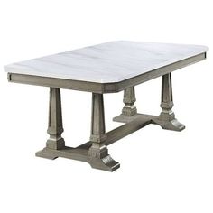 a white marble top dining table with metal legs and two columns on the base,