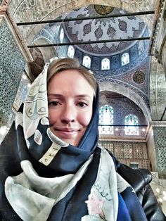 a woman wearing a blue and white scarf in an ornate building with stained glass windows